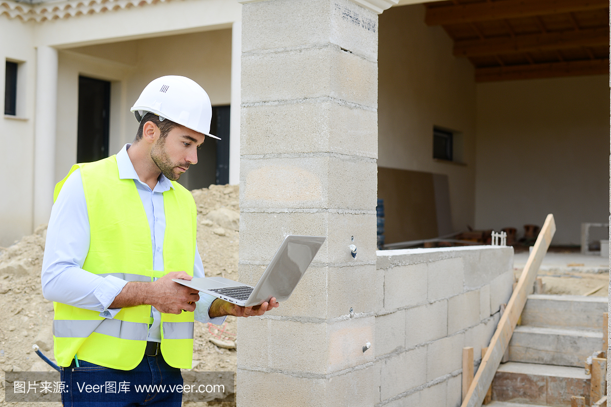 英俊的年轻人工头建筑师监督一个新房子建筑工地